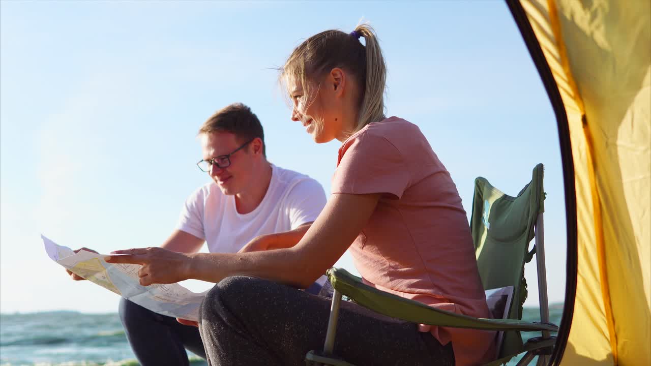Couple reading a map at the beach while camping