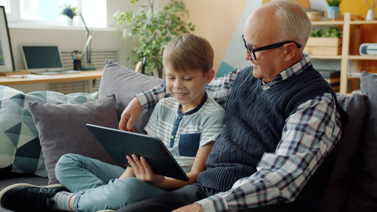 Grandfather and grandson using tablet together at home