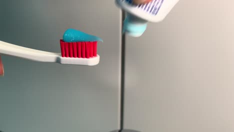 putting toothpaste on white red plastic toothbrush