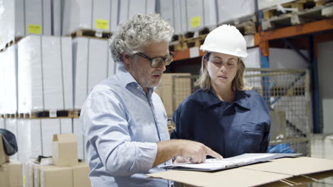 serious safety inspector checking warehouse with female worker