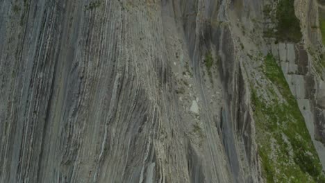 drone pedestal ascends rock flysch sea cliffs in zumaia spain, tilt down