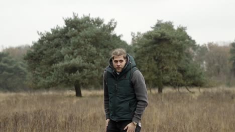 man standing alone in a field in the middle of the forest