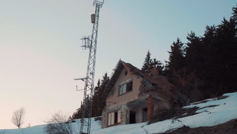 una vieja casa abandonada y medio arruinada en la ladera de una montaña cubierta de nieve