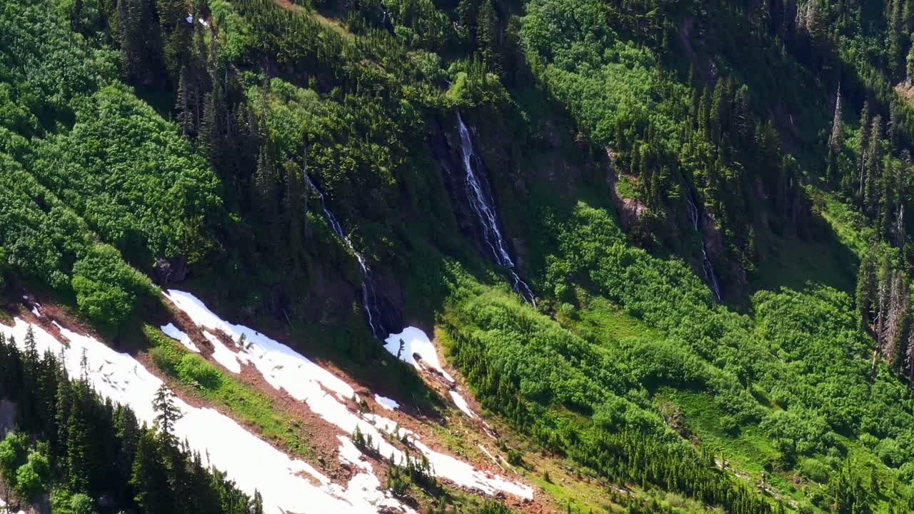 Scenic aerial shot of a small waterfall in a lush green forest on the side of a mountain in the Pacific Northwest, Washington State