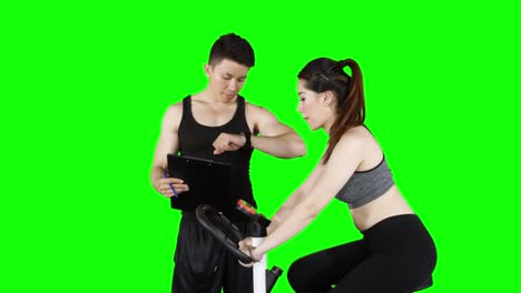 personal trainer training woman on exercise bike