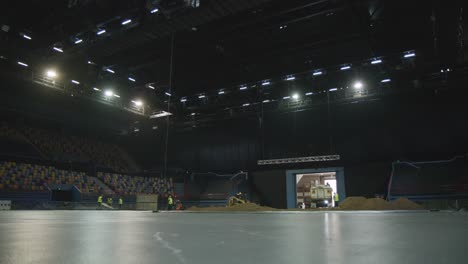 workers flatten dirt in a large stadium in preparation for an indoor dirt event