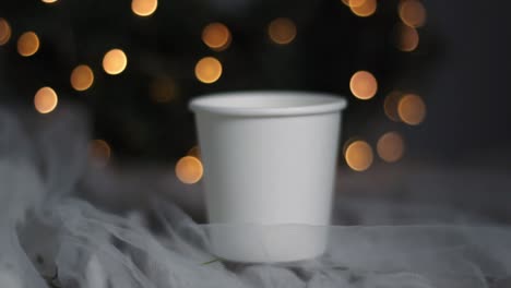 Handaufnahme-Eines-Weihnachtspappbechers-Mit-Bokeh-Lichterketten