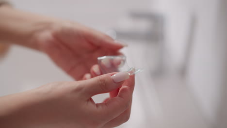 la mano de la mujer sostiene un parche transparente para la piel alrededor de los ojos. la dama con manicura toma parches cosméticos hidratantes para los ojos en las manos en la ducha en cámara lenta