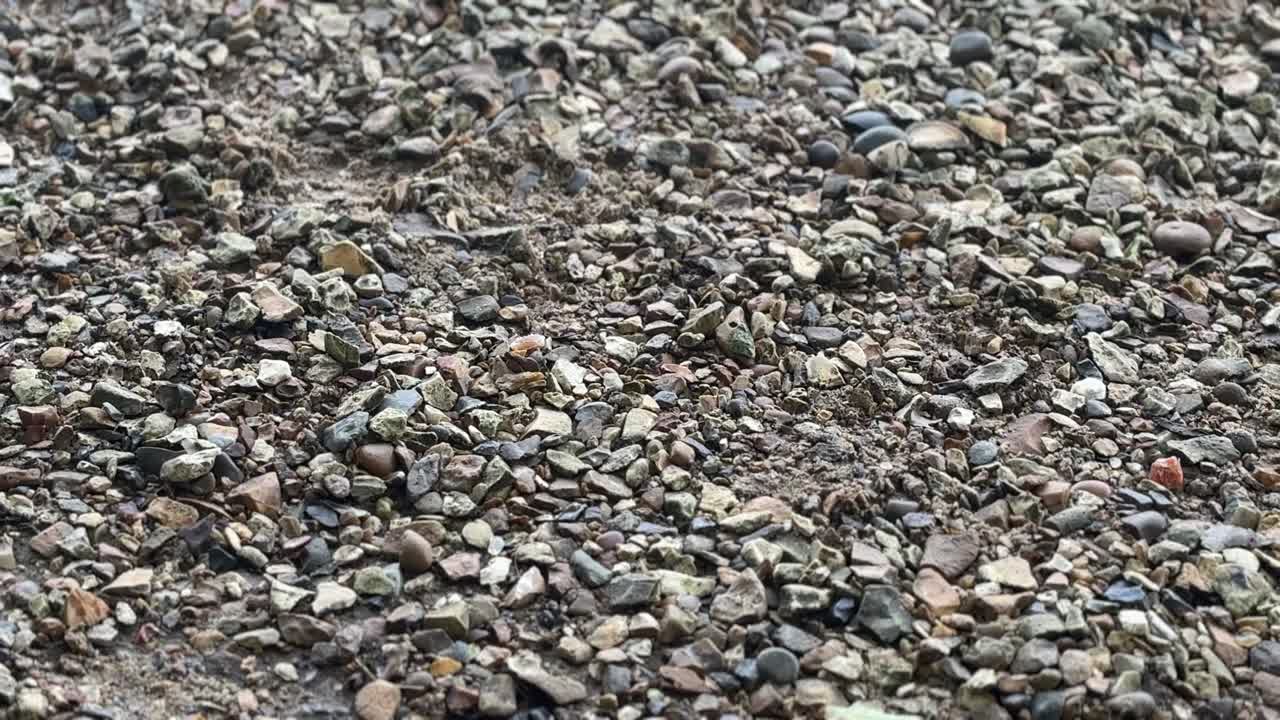 A detailed close-up of natural, rugged base gravel, showcasing its rich texture and diverse mix of earthy tones. Perfect for illustrating construction, landscaping, and outdoor stability.
