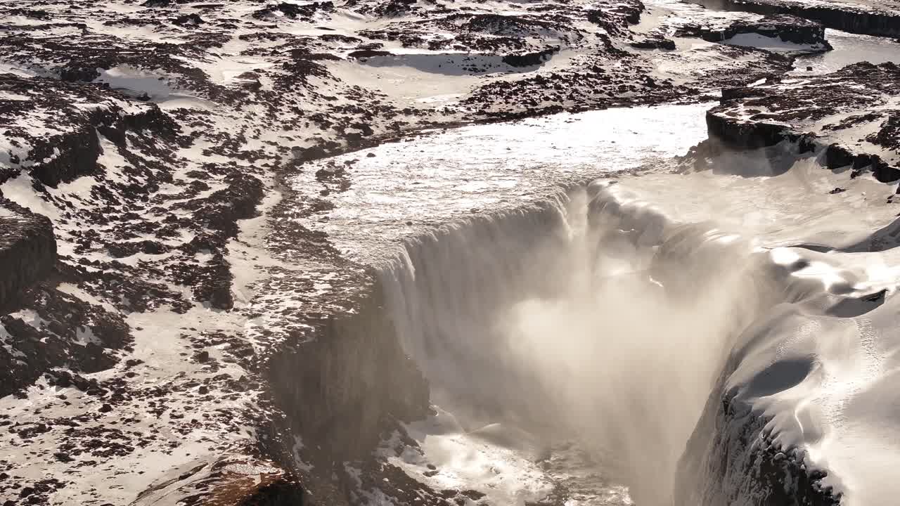 Sunlight pierces icy mist over Dettifoss waterfall in north Iceland's dramatic snowy canyon