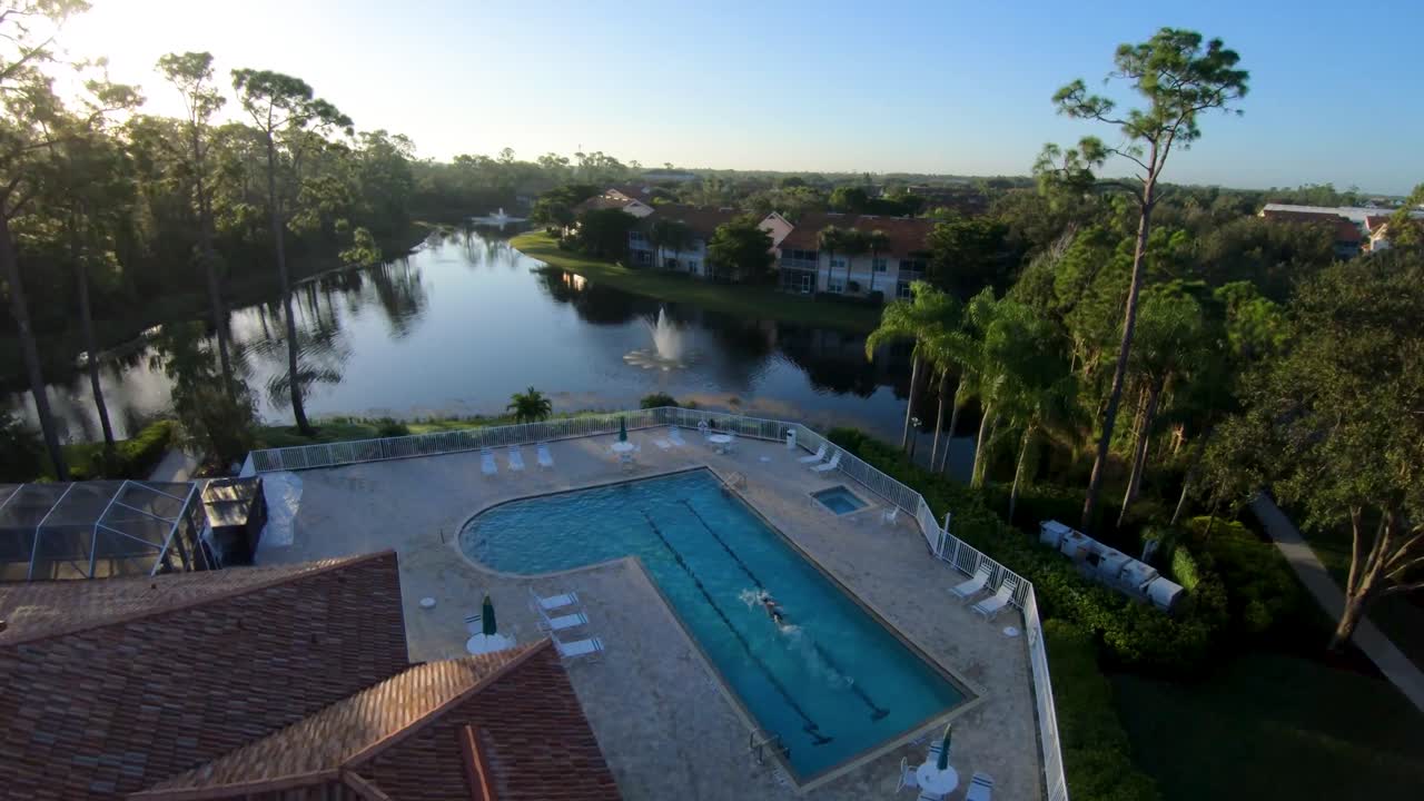 imágenes de drones de un hombre zambulléndose en una piscina comunitaria cerrada de florida y nadando