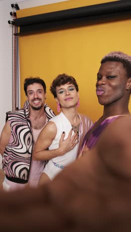 three trans people posing and smiling while taking selfie in a photo studio