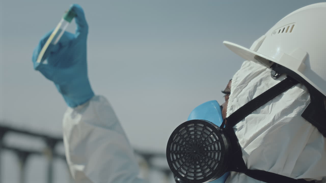 Ecologists in Protective Uniform Examining Test Tube with Sample