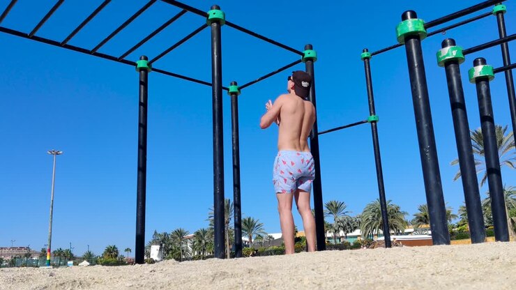 male doing pull ups, outdoor workout spot at a sunny beach, fit caucasian man doing bodyweight training calisthenics, shot in fuerteventura