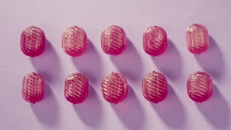 pink lollipops, candies, bonbons on purple background. summer bright texture studio shot for store, supermarket, close up top view, zoom. children's favorite sweets made of sugar.