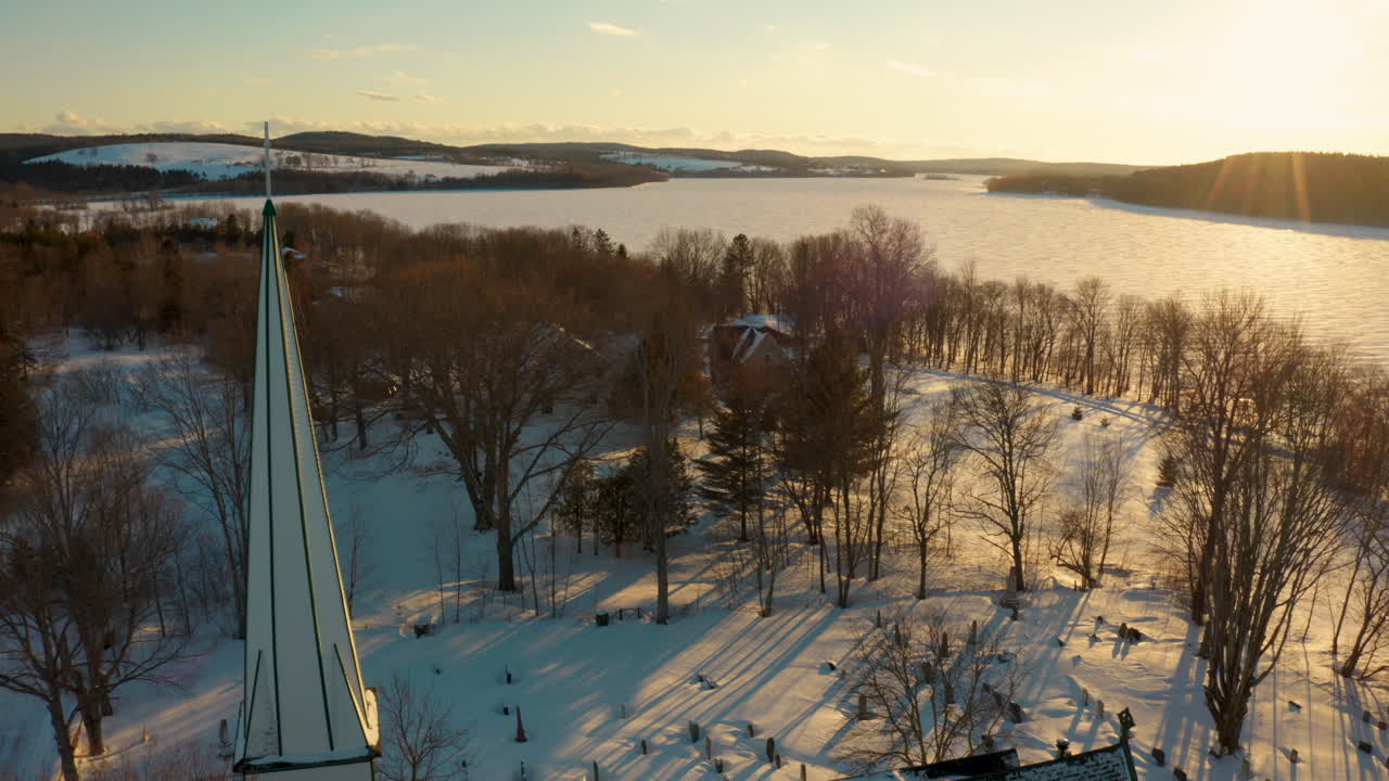 석양에 작은 마을과 얼어붙은 강 위를 날아다니는 멋진 공중 드론 전망