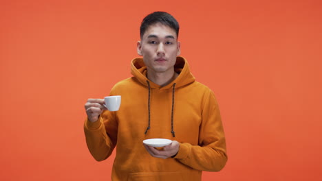 man drinking coffee in orange hoodie