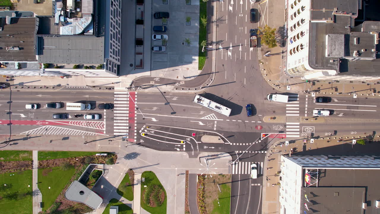 Aerial top down shot of driving bus and cars on road junction in Gnom City at Sunny day