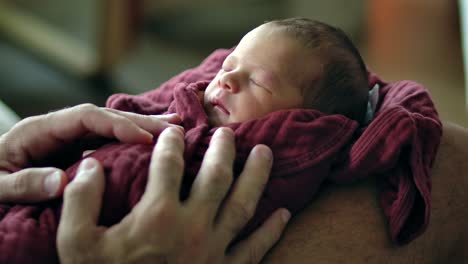 loving hands holding sleeping baby wrapped in blanket - close up