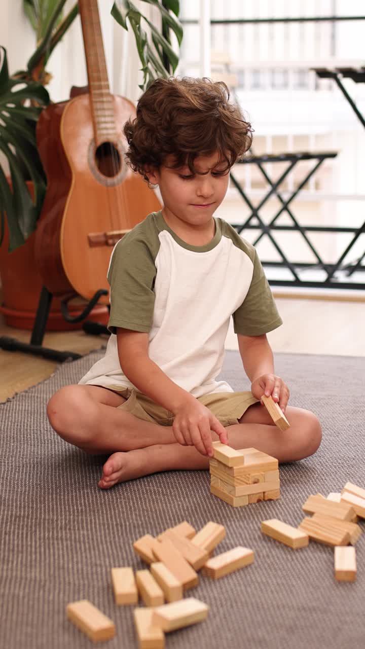 Young boy building wooden block tower at home