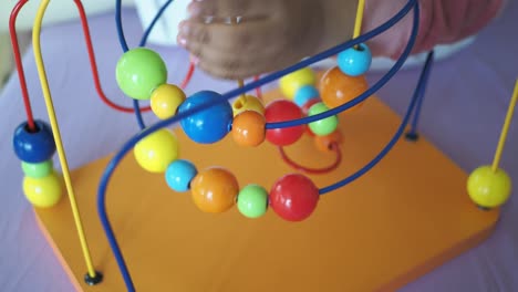 child playing with a colorful bead maze toy