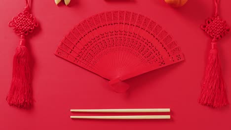 video of close up of chinese fan and decorations on red background