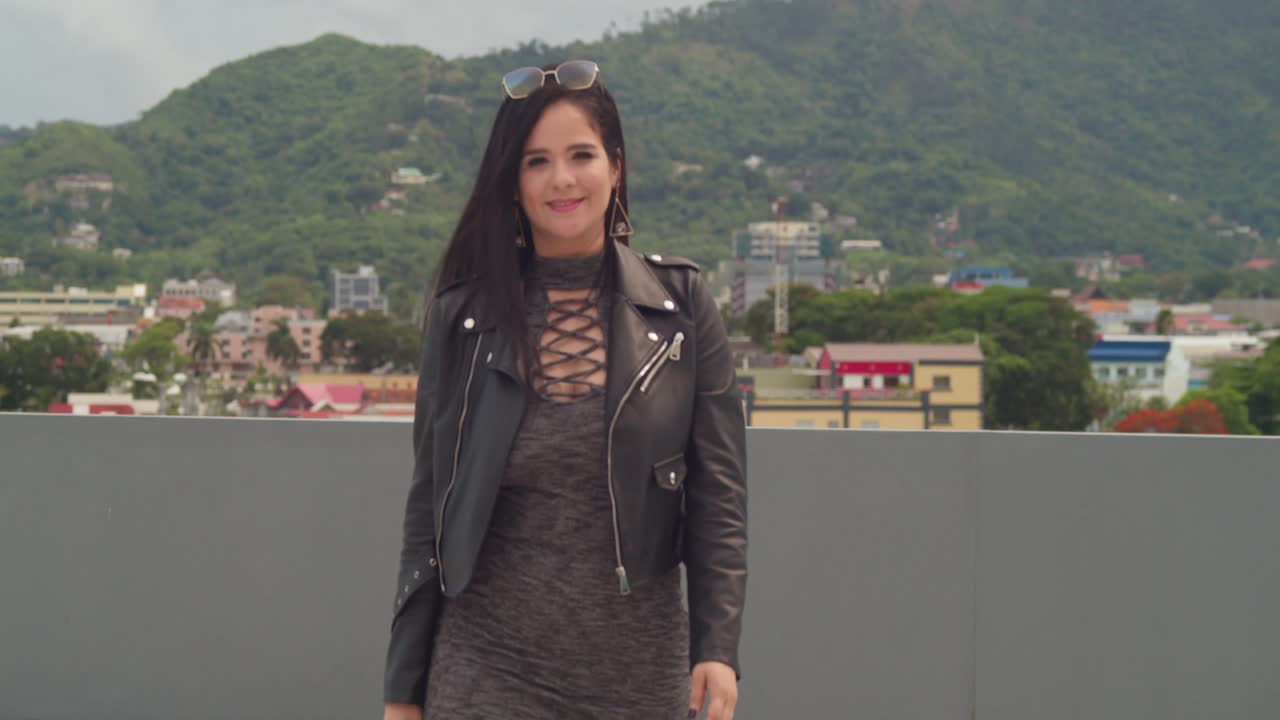 una mujer se divierte en un techo, con el hermoso paisaje urbano de port of spain, trinidad, detrás de ella