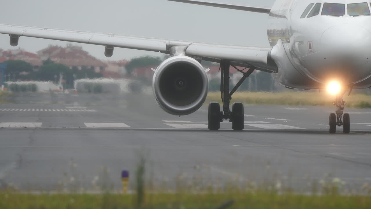 Airplane is taxiing on the runway, with blurred airport background and overcast sky, low angle shot