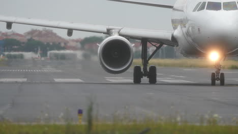 airplane is taxiing on the runway, with blurred airport background and overcast sky, low angle shot