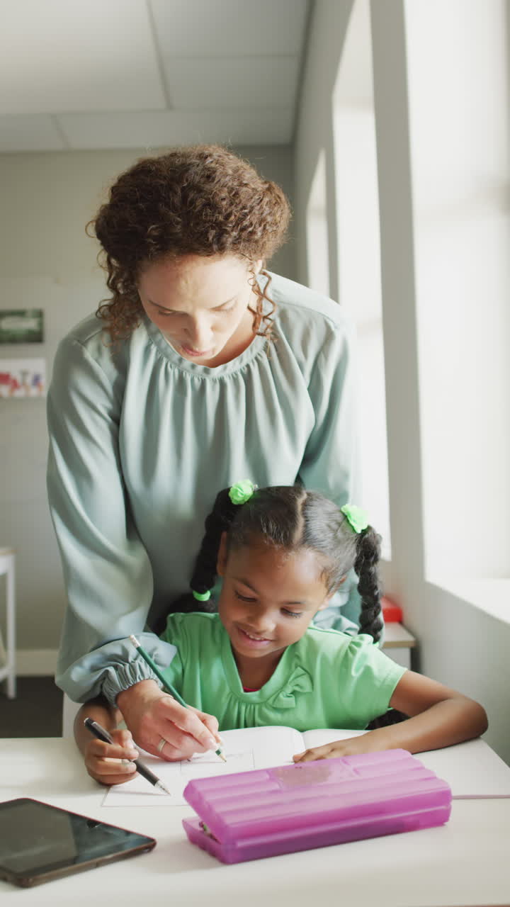 video vertical de una feliz maestra caucásica con una estudiante afroamericana aprendiendo