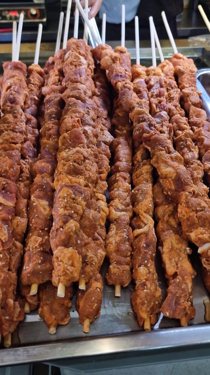 Vista verticale di spiedini di carne fritti in un mercato di street food asiatico, primo piano