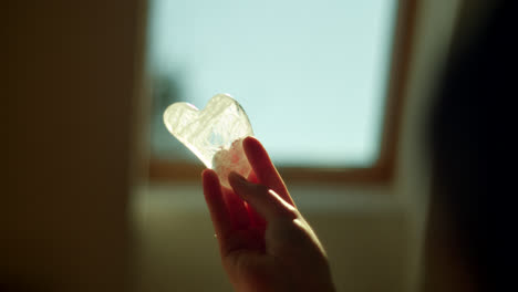 person holding heart-shaped quartz gua sha tool