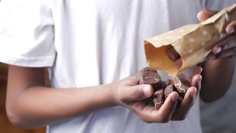 child boy pouring chocolate candy from a packet ,