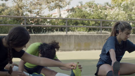 Jugadoras-De-Fútbol-Sentadas-En-El-Campo-Y-Estirando-Las-Piernas