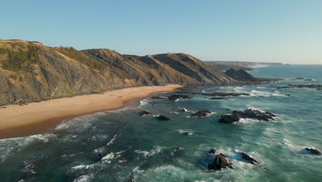 Luftaufnahme-Eines-Atemberaubenden-Strandes-Mit-Sonnenuntergangslicht-Und-Wellen,-Die-Am-Ufer-An-Der-Westküste-Portugals-Krachen