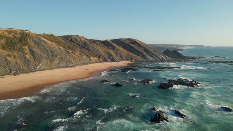 aerial view of stunning beach with sunset light and waves crashing on the shore on the west coast of portugal