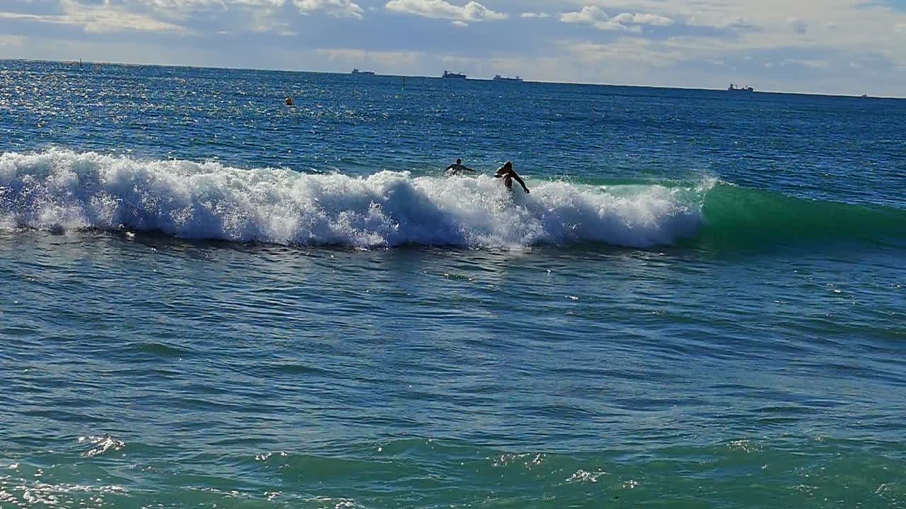 Slow motion (120fps): male surfers trying to catch the wave in Barcelona, Spain