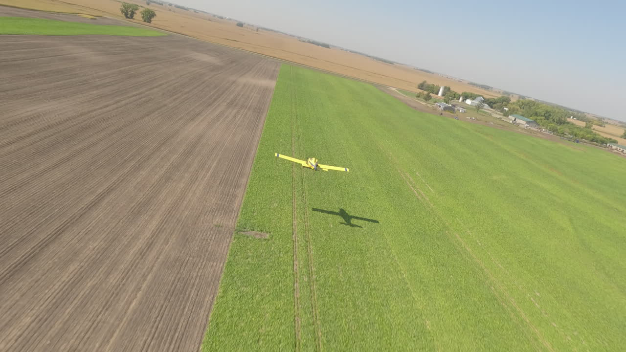 시골 잔디 활주로 위에서 낮게 날아다니는 작은 작물 뿌리기 비행기의 fpv 드론 뷰