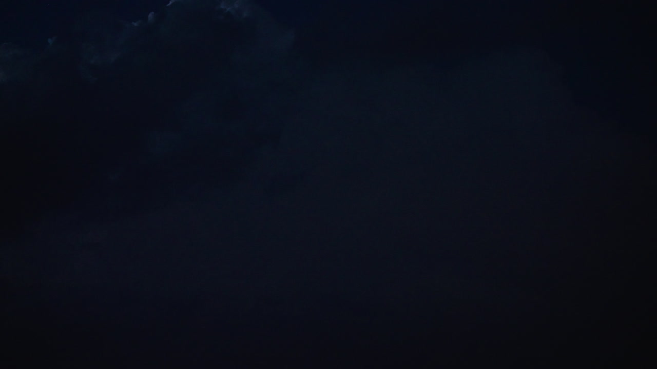 Lightning illuminates night sky revealing textured clouds and powerful motion