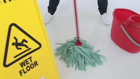 woman cleaning near a caution sign