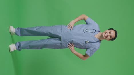 full body of asian male doctor with stethoscope putting hands on his hip and smiling on green screen background in the hospital