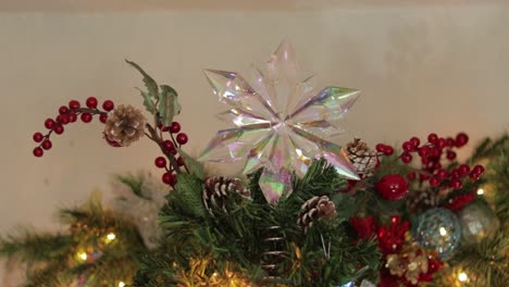 placing opalescent snowflake star decoration on top of christmas tree