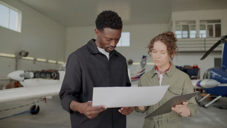 two technicians reviewing aircraft documents and plans in hangar