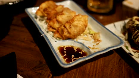 palillos para comer levantando gyoza de un plato de salsa