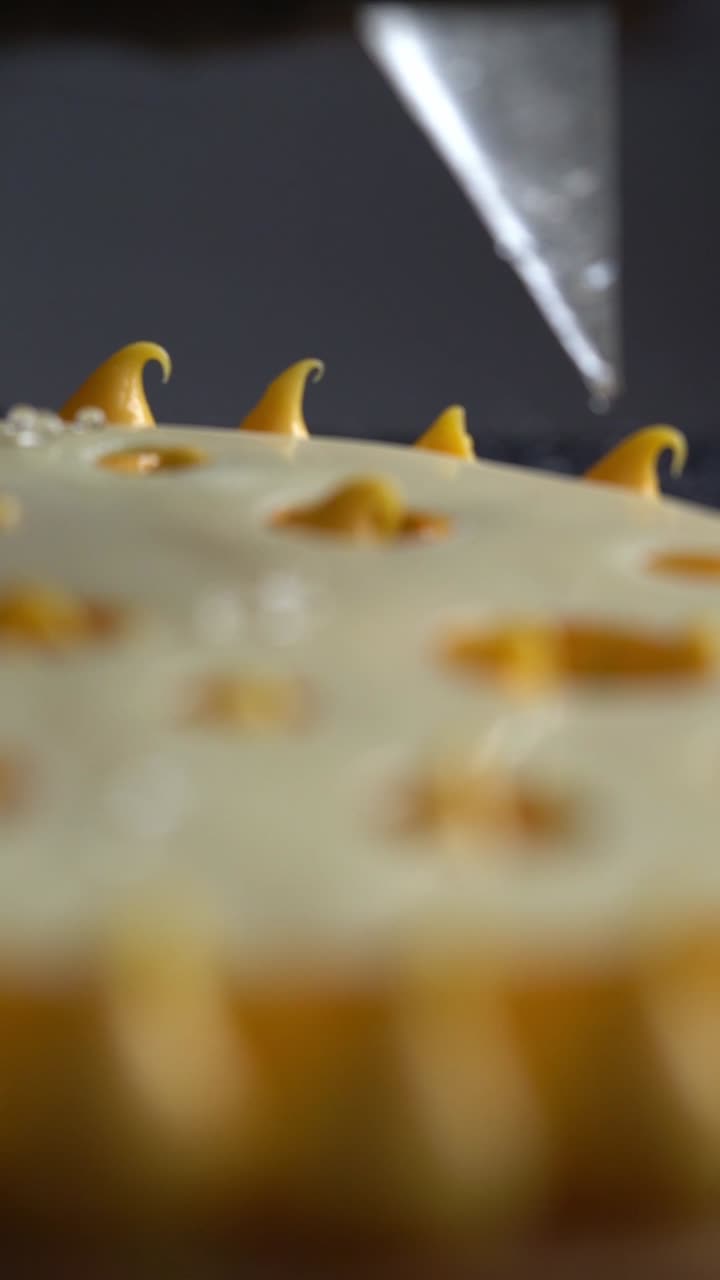 Un capo chef versa delle gocce di crema su un moderno dolce giallo, primo piano