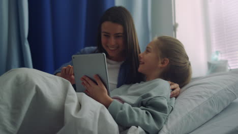 una niña sonriente jugando con su madre en la sala. un padre de apoyo visitando a un niño enfermo.