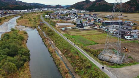 aerial drone view of japanese countryside with children running on road next to river in gifu japan