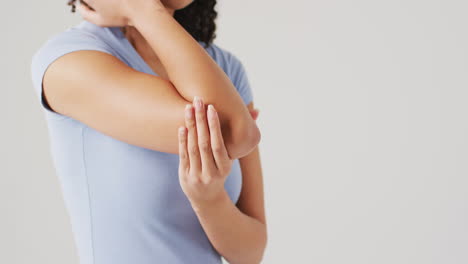 video of biracial woman touching her elbow on white background