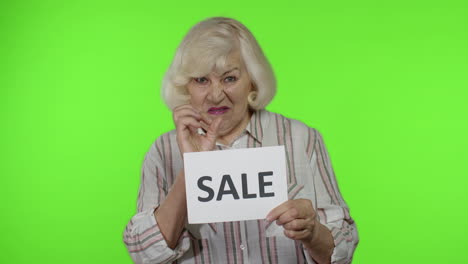 Grandmother-showing-Sale-word-inscription-note,-satisfied-with-low-prices,-shopping-on-Black-Friday