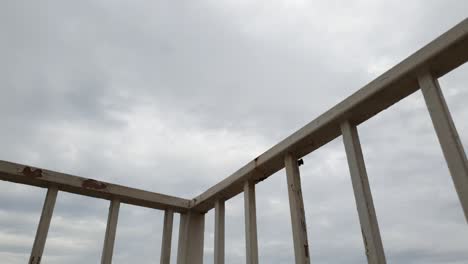 Old-white-rusty-guard-rail-bars-with-a-beautiful-long-cloud-time-lapse-in-the-background